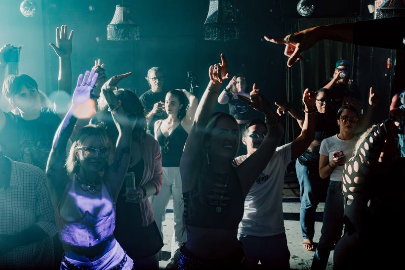 A packed dance floor with hands in the air